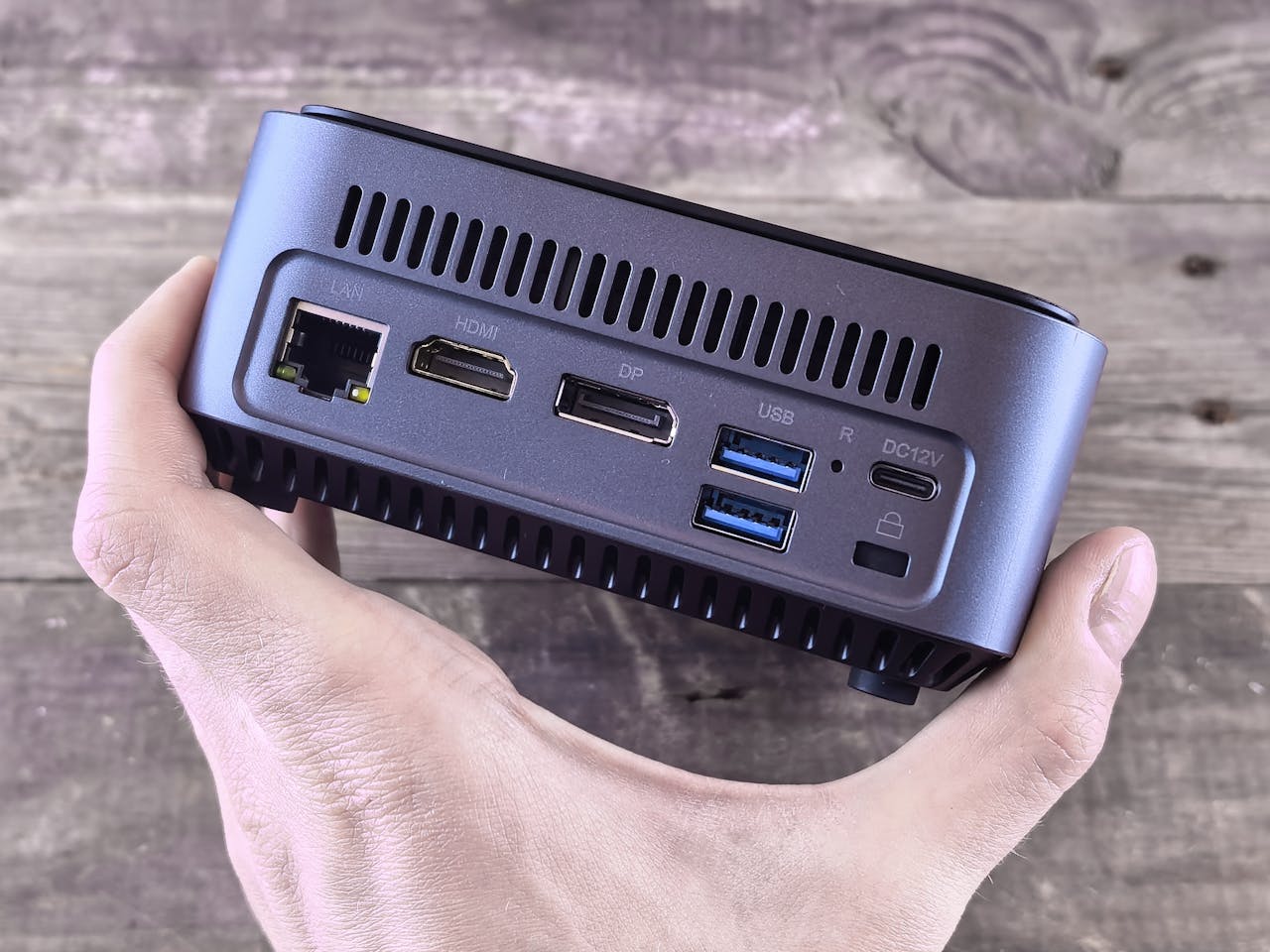 Close-up of a compact computer showing various ports held in a person's hand.